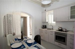 a kitchen with white cabinets and a table with plates on it at Villa ANASA private Pool & Jacuzzi 8pax at Panormos in Panormos Mykonos