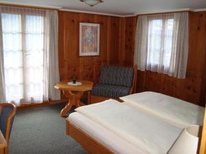 ein Schlafzimmer mit einem Bett, einem Stuhl und einem Tisch in der Unterkunft Hotel Restaurant Alpenblick in Ernen