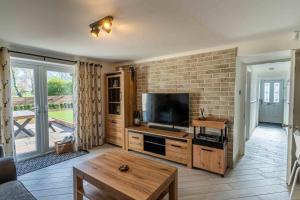 een woonkamer met een televisie en een bakstenen muur bij 1 The Cottage in Upholland