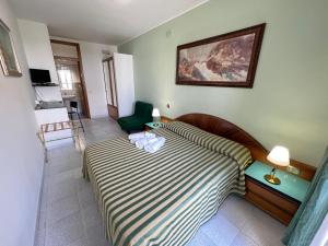 a bedroom with a bed and a green chair at Hotel Minerva in Otranto