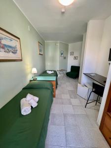una camera d'albergo con 2 letti verdi e una scrivania di Hotel Minerva a Otranto