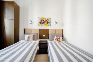 two beds in a small room with white and blue stripes at Francesco Romestay - Termini in Rome