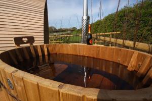 a wooden plunge pool with a bottle of wine at Armadilla 3 at Lee Wick Farm Cottages & Glamping in Clacton-on-Sea