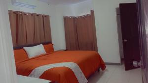 a bedroom with a bed with an orange blanket at Weekendz- Cozy 2BRD Suite in Port Antonio