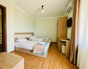 a hotel room with two beds and a desk at Sea Line Hotel in Shekvetili