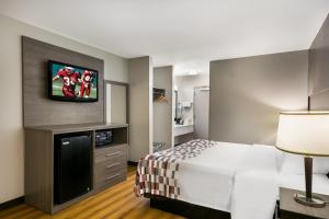 a hotel room with a bed and a flat screen tv at Red Roof Inn Denver in Denver