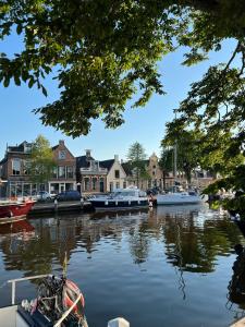 een groep boten aangemeerd op een rivier met huizen bij Dok 20, Lemmer in Lemmer