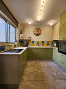 a kitchen with green cabinets and a clock on the wall at The house of love in Meitar