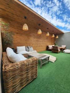 un patio con muebles de mimbre en una alfombra verde en The house of love, en Meitar