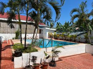 een zwembad met palmbomen en een gebouw bij Beth's Villa in Moalboal