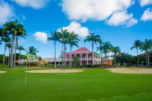 a golf course with palm trees and a building at Villa PINK in Saint-François