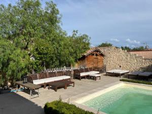 a patio with benches and a swimming pool next to a building at Gîte Blanche de Rouquette in Paulhan