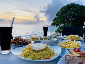 a table with plates of food and drinks on the beach at Thoddoo Beach Holiday Inn in Thoddoo