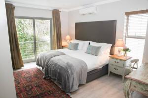 um quarto com uma cama e uma grande janela em 13 La Gratitude Luxury Apartment-with backup power for loadshedding em Stellenbosch