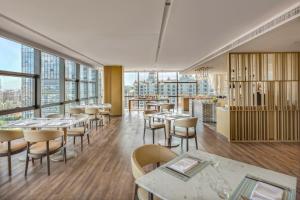 a restaurant with tables and chairs and large windows at Courtyard by Marriott Foshan Gaoming in Foshan