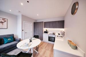 a kitchen and living room with a table and a couch at Pluxa Jade - Prime Harrow, Work Desk & WiFi in Harrow