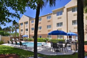 a hotel with chairs and umbrellas next to a pool at Fairfield Inn Jacksonville Orange Park in Orange Park