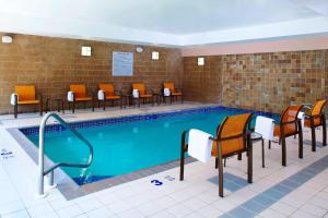 a swimming pool with orange chairs and a row at Courtyard by Marriott Buffalo Amherst/University in Amherst