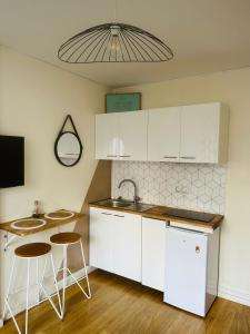 a kitchen with white cabinets and two bar stools at Biarritz, hyper centre, 50M plages, wifi in Biarritz