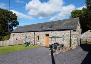 a stone barn with a table and chairs in front of it at Crud y Werin in Llandderfel