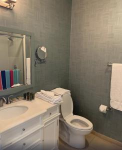 a bathroom with a toilet and a sink and a mirror at Ballard's Beach Resort in New Shoreham