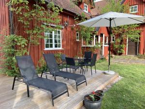 um deque de madeira com cadeiras e um guarda-sol em Villa Linneryd 1 em Linneryd