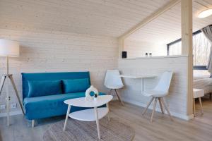 a living room with a blue couch and a table at SKAN-PARK Ferienhäuser & Tiny Houses am Bärwalder See 