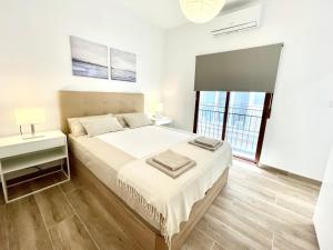 a white bedroom with a bed and a window at Benidorm Old Town House with lounge area in Benidorm