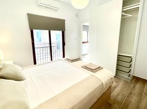 a white bedroom with a large bed and a window at Benidorm Old Town House with lounge area in Benidorm