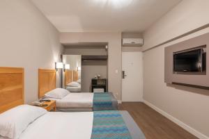 カンピーナスにあるMonreale Express Glicério Campinasのベッド2台、薄型テレビが備わるホテルルームです。