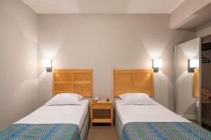 a room with two beds and a nightstand between them at Monreale Express Glicério Campinas in Campinas