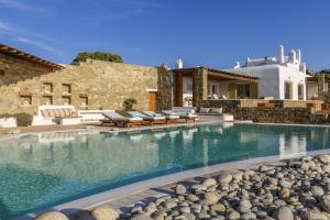 a swimming pool with chairs and a house at Villa Yasmina in Tourlos