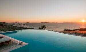 a swimming pool with a sunset over the ocean at Villa Yasmina in Tourlos