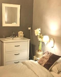 1 dormitorio con 1 cama, lavamanos y un jarrón de flores en Chambre d'hôte, en Castex