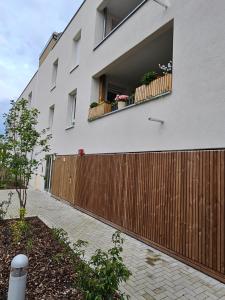 biały budynek z drewnianym płotem i oknem w obiekcie Superbe appartement dans un quartier neuf et calme w Strasburgu