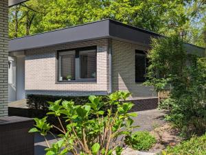 una pequeña casa con techo negro en Luxe bungalow "Zomeroord", en Beekbergen