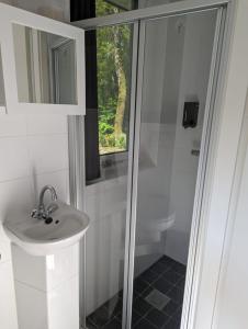 een witte badkamer met een wastafel en een douche bij Luxe bungalow "Zomeroord" in Beekbergen
