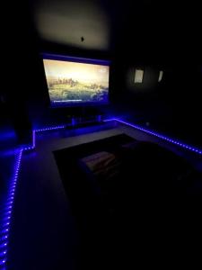 um quarto escuro com uma televisão e uma luz azul em Le CinéGlam Spa em Margny-lès-Compiègne