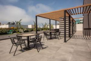 un patio con mesas y sillas en la azotea en SoHo by Wynwood House, en Lima
