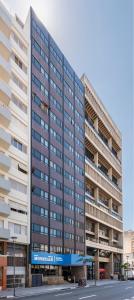 un gran edificio de oficinas con un cartel azul. en Monreale Express Glicério Campinas, en Campinas