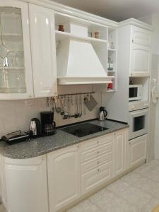 a white kitchen with white cabinets and a sink at Guesthouse NADIA in Senj