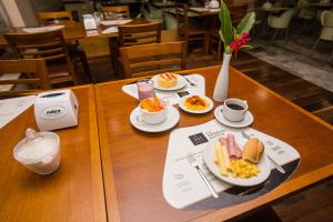 - une table en bois avec des assiettes de nourriture pour le petit-déjeuner dans l'établissement Rede Andrade Pampulha, à Belo Horizonte