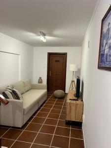 ein Wohnzimmer mit einem Sofa und einem TV in der Unterkunft Coast Beach Apartment - Praia da Areia Branca in Praia da Areia Branca