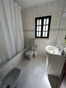 ein weißes Bad mit einem Waschbecken und einem WC in der Unterkunft Coast Beach Apartment - Praia da Areia Branca in Praia da Areia Branca