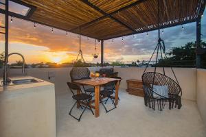 Wayuum Suites Cozumel Oasis in Paradise في كوزوميل: فناء مع طاولة وكراسي وغروب الشمس