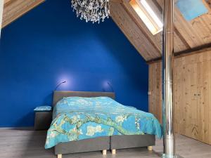 a blue bedroom with a bed with a blue wall at Appartement Elperhof 16A in Schoonloo