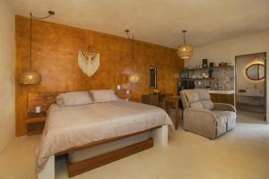 Wayuum Suites Cozumel Oasis in Paradise في كوزوميل: غرفة نوم بسرير وكرسي