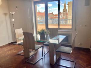 a dining room with a glass table and chairs and a window at Apartamentos Azafranal-PARKING GRATIS- in Salamanca