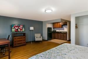 a bedroom with a bed and a desk and a kitchen at HomeTowne Studios by Red Roof Denver, PA in Denver