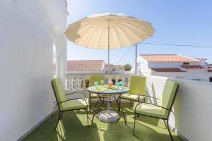 a table and chairs on a balcony with an umbrella at Bambus House Green in Quarteira